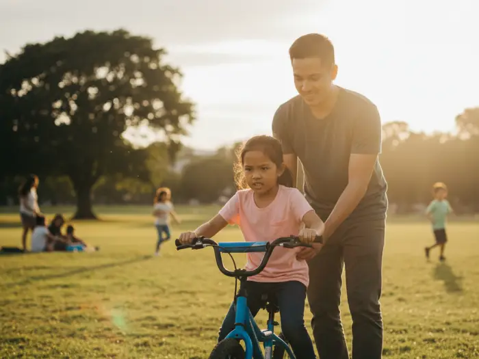 Filipino child learning new skill outdoors with parent support.