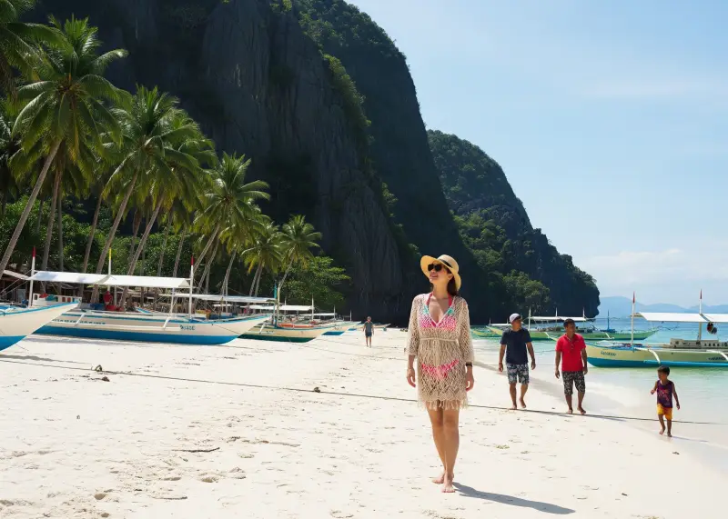 Filipina in bikini and net dress enjoying the beach at Gigantes Islands with cliffs and boats in the background.