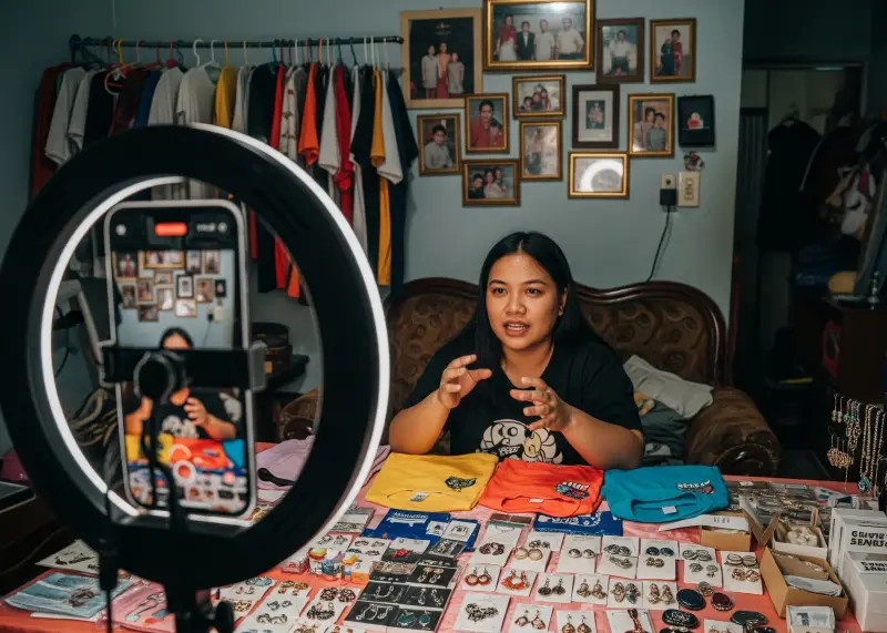 Filipino TikTok live seller showcasing products in a modest sala.