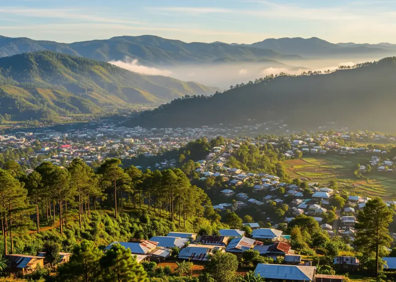 Panoramic view of Malaybalay City with pine-covered mountains and mist.