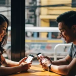 Filipino couple smiling while checking a dating app in a Manila café
