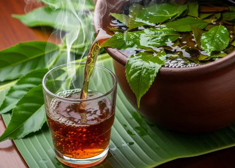 Tsaang Gubat herbal tea freshly brewed in a clay pot and poured into a glass.