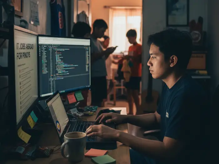 Filipino IT worker coding at home while viewing IT jobs abroad for Pinoys