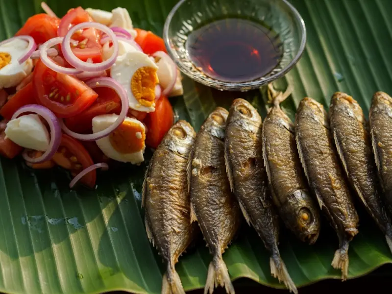 Fried galunggong served with tomato and salted egg ensalada on a banana leaf plate.