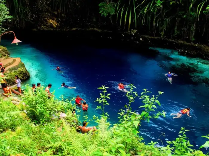 Visitors swimming in the clear blue waters of the Enchanted River in Hinatuan.