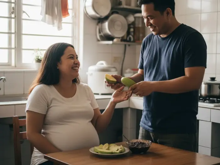 Pregnant Filipina satisfying green mango cravings as her husband playfully helps.