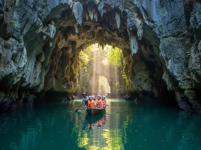 Tourists entering the limestone cave entrance of Sohoton Cove by paddleboat in Bucas Grande.