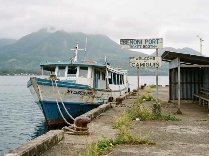 camiguin travel guide benoni port arrival Benoni Port in Camiguin with a ferry docked beside the pier and hills behind it, created for a Camiguin Travel Guide explaining routes and how to reach the island.