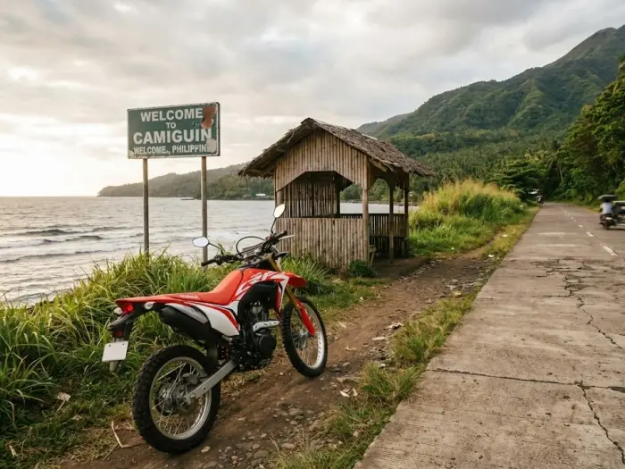 camiguin travel guide transport motorbike road A motorbike parked along a scenic Camiguin coastal road with sea and mountain views, created for a Camiguin Travel Guide explaining transport options.