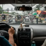 Filipino driver signaling and driving courteously on a busy Philippine street with jeepneys and tricycles around.